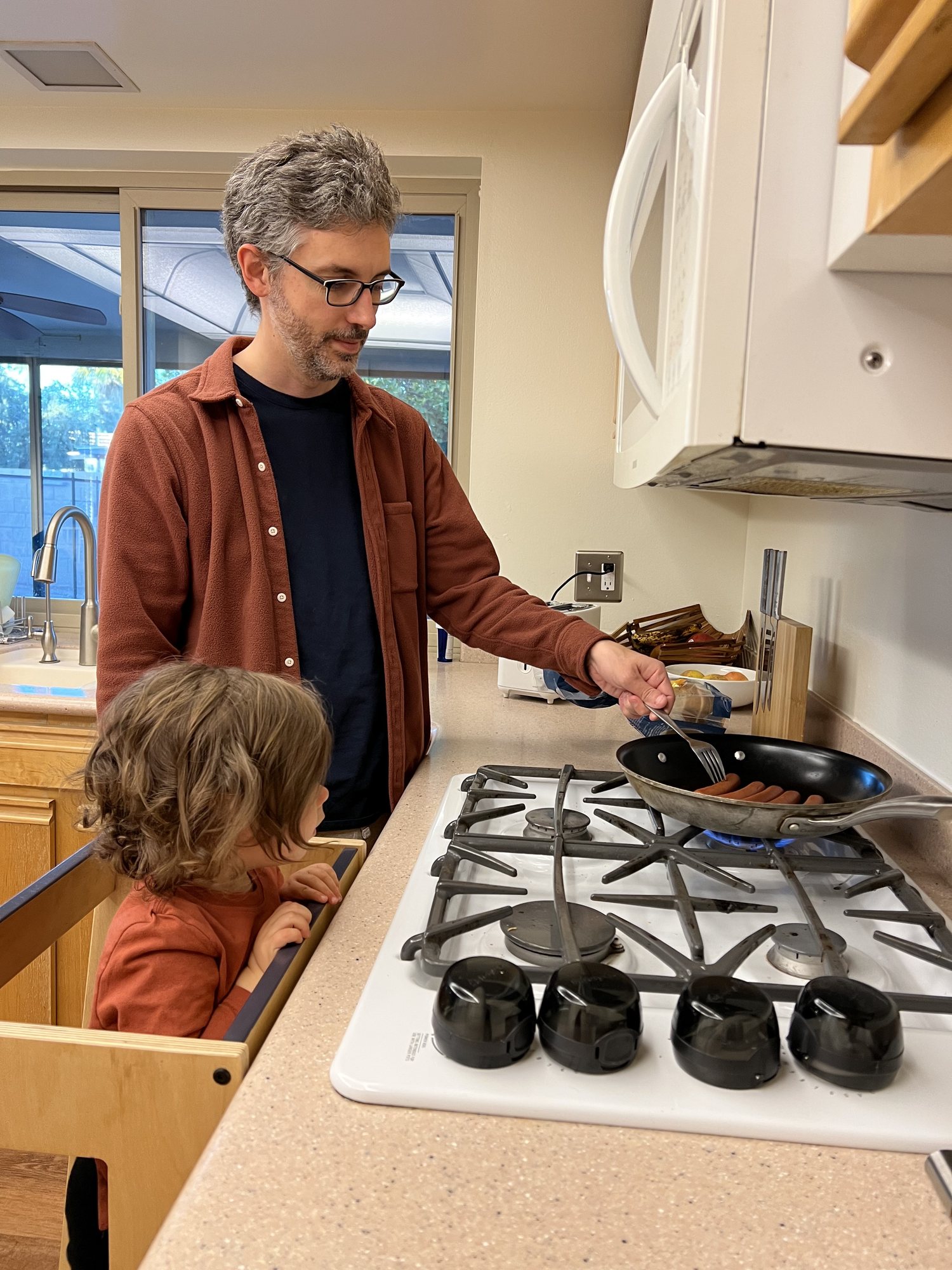 Dad teaching Nora how to cook his specialty - hot dogs.